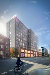 a person riding a bike in front of a building at Moxy Aarhus in Aarhus