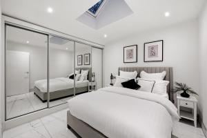 a white bedroom with a large bed and a window at Luxury Ascot Villa Steps from Royal Ascot, 5 mins to Legoland Windsor Resort, 10 mins to Windsor Castle in Ascot