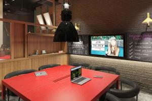a red table with a laptop on it in a restaurant at Moxy Belgrade Skadarlija in Belgrade