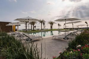 a pool with benches and umbrellas and palm trees at Delta Hotels by Marriott Riviera Veracruz in Heroica Alvarado
