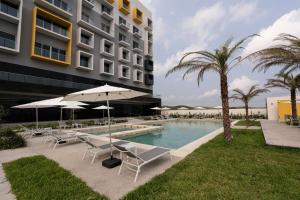 a pool with chairs and umbrellas next to a building at Delta Hotels by Marriott Riviera Veracruz in Heroica Alvarado
