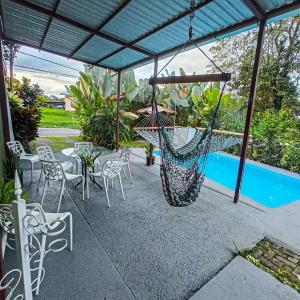 a patio with a hammock and chairs and a pool at Arenal Views, Pool & 5min to Waterfall & Town in Fortuna