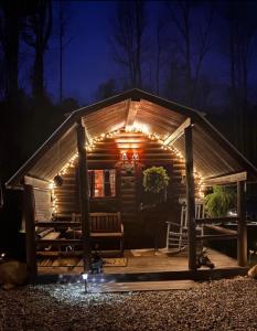 a log cabin with lights on it at night at The Dapper Duck Log Cabin in Cosby
