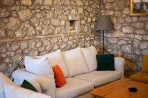 a living room with a white couch and a stone wall at Achyronas 1840 Stone House in Graviá