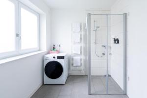 a bathroom with a washing machine and a shower at Tonirooms 2 Zimmer Apartment Eisvogel in Straubing