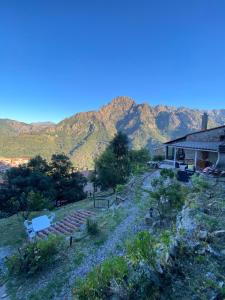 a house on a hill with mountains in the background at Maison de charme en pierre in Porto Ota +5 photos