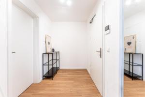 a hallway with white walls and a wooden floor at Tonirooms 2 Zimmer Apartment Eisvogel in Straubing