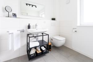 a white bathroom with a sink and a toilet at Tonirooms 2 Zimmer Apartment Eisvogel in Straubing +3 photos