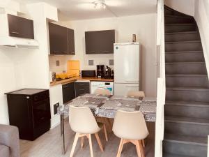 a kitchen with a table and chairs and a refrigerator at Maisonnette du bonheur in Courseulles-sur-Mer