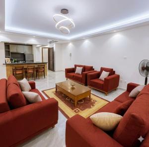 a living room with red couches and a table at Decent brand new flat with garden view in New cairo +10 photos
