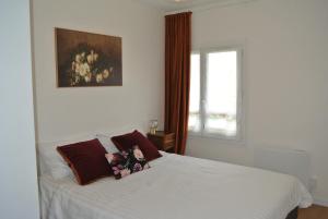 a bedroom with a white bed with pillows and a window at Le Jardin de Madison in Cessy