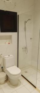 a white bathroom with a toilet and a shower at شقة واحة رتيل الفندقية in Al-ʿUla