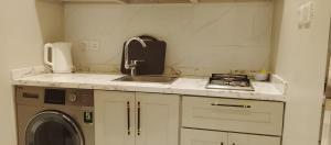 a kitchen with a sink and a washing machine at شقة واحة رتيل الفندقية in Al-ʿUla