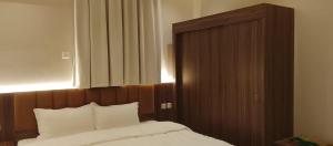 a bedroom with a bed with a wooden head board at شقة واحة رتيل الفندقية in Al-ʿUla