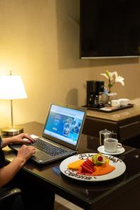 a person sitting at a desk with a laptop and a plate of food at Gamma Cuernavaca Puerta Paraiso in Cuernavaca