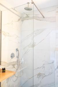 a shower in a bathroom with white marble walls at Theoni Garden in Parga +30 photos