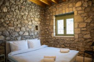 a bedroom with a bed in a stone wall at Achyronas 1840 Stone House in Graviá