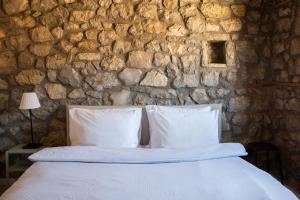 a bed with white pillows in a stone wall at Achyronas 1840 Stone House in Graviá