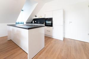 a white kitchen with white cabinets and a wooden floor at Tonirooms 3-Zimmer Buntspecht in Straubing