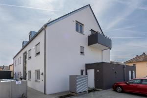 a white house with a red car parked in front of it at Tonirooms 3-Zimmer Buntspecht in Straubing