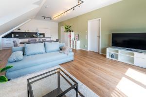 a living room with a blue couch and a flat screen tv at Tonirooms 3-Zimmer Buntspecht in Straubing