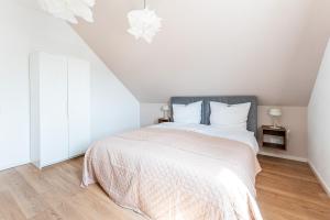a white bedroom with a large bed with white sheets at Tonirooms 3-Zimmer Buntspecht in Straubing