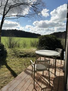 a table and a chair on a deck with a field at Tiny House 2 mit Garten in der Lüneburger Heide in Soltau