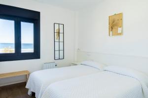 two beds in a white room with a view of the ocean at Hostal Montevideo Camino De Santiago & Beachfront in Nigrán +62 photos