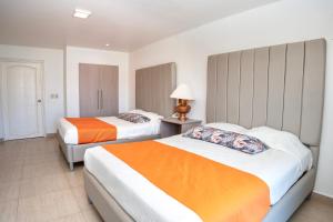 a hotel room with two beds with orange and white at Hotel Palma Real in Sambo Creek