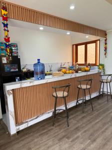 a kitchen with three bar stools and a counter at Casa La Herencia in Huaral