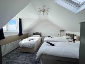 a attic bedroom with three beds and a ceiling at Harbour Heights B&B in Portrush