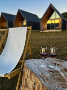 two glasses of wine sitting on a wooden table at NORTH VILLAS Žabljak in Žabljak