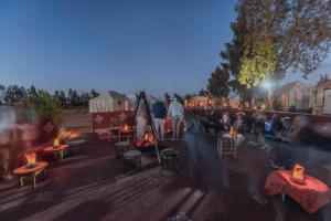a group of people sitting around tables with candles at Camels House in Merzouga