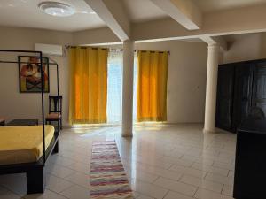 a bedroom with yellow curtains and a bed and a rug at Luciana annexe in Mbour