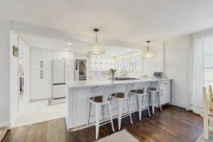 a kitchen with white cabinets and a bar with stools at The Hilltop in Waterbury