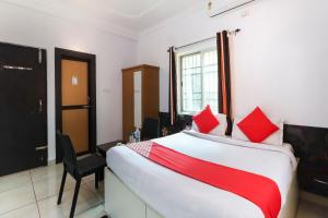 a bedroom with a large bed with red pillows at Capital O The Tulip in Rānchī +17 photos