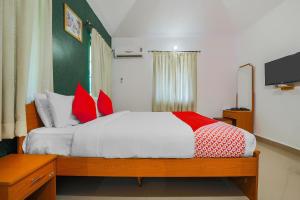 a bedroom with a bed with red pillows at Hotel O The Goan Courtyard in Goa