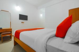 a bedroom with a bed with red and white pillows at Hotel O The Goan Courtyard in Goa