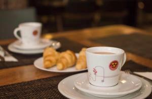 two cups of coffee and plates of pastries on a table at Flat de Luxo Aeroporto Congonhas - Hotel in São Paulo +209 photos