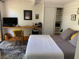 a bedroom with a bed and a desk with a computer at Cabane dans la verdure in Lège-Cap-Ferret
