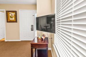 a room with a table and a television on a wall at Cozy 1st floor condo with golf course view in New Bern