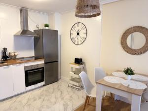a kitchen with a table and a clock on the wall at Apartamento Cueto II in Soto del Barco