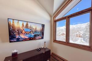 a tv on a wall in a room with a window at Benchmark Dr 101 ~ Guest House in Telluride