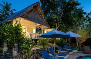 a house with blue chairs and an umbrella at The Dafish Ceningan in Nusa Lembongan