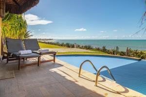 a swimming pool with a chair next to the ocean at Pousada Spa dos Amores in São Miguel do Gostoso