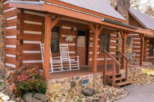 a log cabin with two chairs on the porch at Copeland Creek- Tiny Cabin in Sevierville