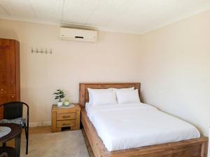 a bedroom with a bed with white sheets and a table at Olive tiny house in Tuval