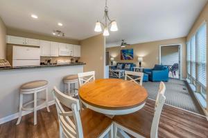 a kitchen and living room with a wooden table and chairs at Golf Course Condo with Pools & Family Fun in New Bern