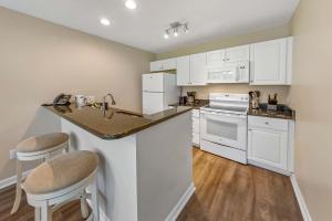 a kitchen with white cabinets and white appliances at Golf Course Condo with Pools & Family Fun in New Bern