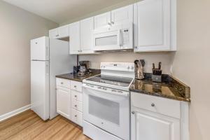 a white kitchen with white appliances and white cabinets at Golf Course Condo with Pools & Family Fun in New Bern +20 photos